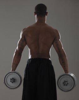 Physically fit man lifting dumbbells. Photographe : Mike Kemp