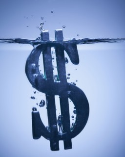 Dollar symbol sinking in water. Photographe : Mike Kemp