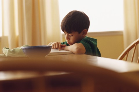 Young boy reading at the kitchen table. Photographe : Rob Lewine