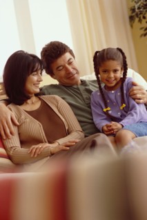 Young girl and her parents relaxing on the couch. Photographe : Rob Lewine