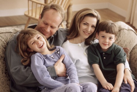 Family sitting together on the couch. Photographe : Rob Lewine