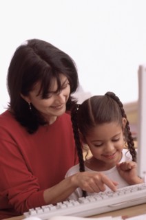 Mother teaching daughter how to use the computer. Photographe : Rob Lewine