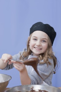 Young girl holding a mixing spoon. Photographe : Dan Bannister