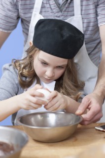 Young girl cracking an egg. Photographe : Dan Bannister