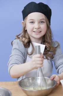 Young girl mixing with a whisk. Photographe : Dan Bannister