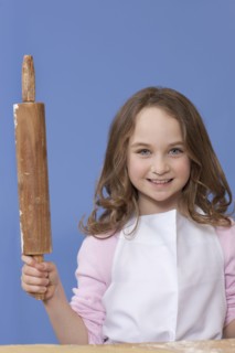Young girl holding a rolling pin. Photographe : Dan Bannister