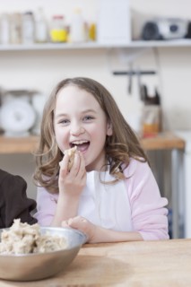 Young girl eating cookie batter. Photographe : Dan Bannister