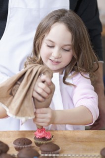 Young girl decorating cupcakes. Photographe : Dan Bannister
