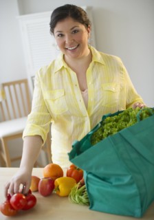 Woman unpacking vegetables from grocery bag.