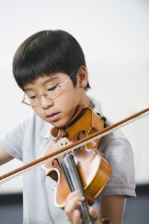 Elementary school student playing violin in music class.