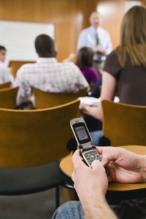 College student texting in lecture hall.
