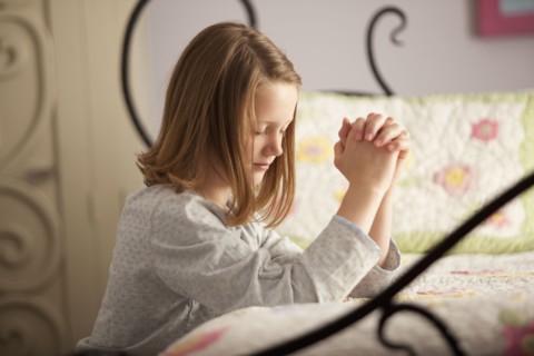 Young girl praying before bed. Photo : Mike Kemp