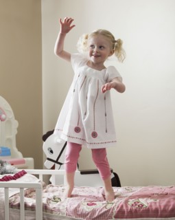 Young girl dancing on her bed. Photo : Mike Kemp