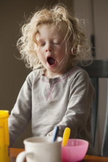 Yawning child at the breakfast table. Photo : Mike Kemp