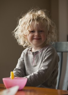 Young girl sitting at breakfast table. Photo : Mike Kemp