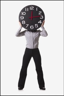 Businesswoman holding clock in front of her face. Photo : Mike Kemp