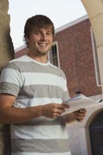 Happy teenage boy holding schoolwork. Photo : Stewart Cohen