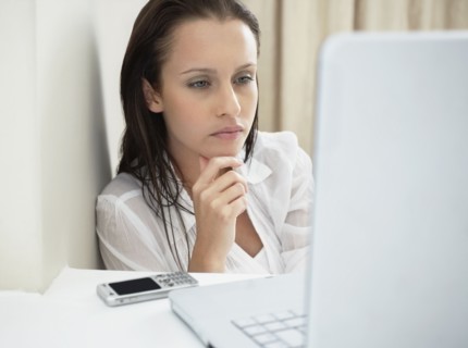 Woman deep in thought while looking at laptop. Photo : momentimages