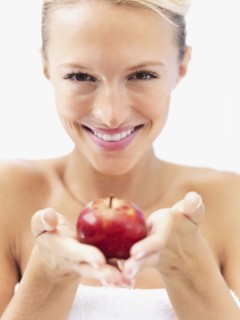 Blond woman holding an apple. Photo : momentimages