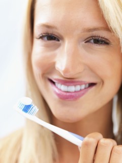 Woman holding a toothbrush. Photo : momentimages