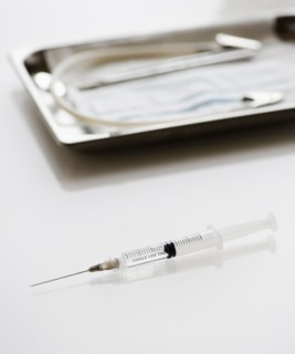 Syringe beside tray of medical supplies. Photo : Jamie Grill