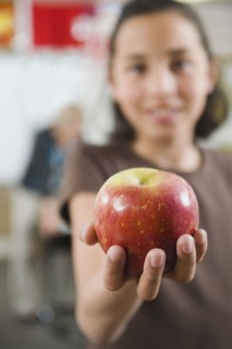 Elementary student holding an apple in her hand.