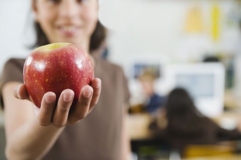 Elementary student holding an apple in her hand.