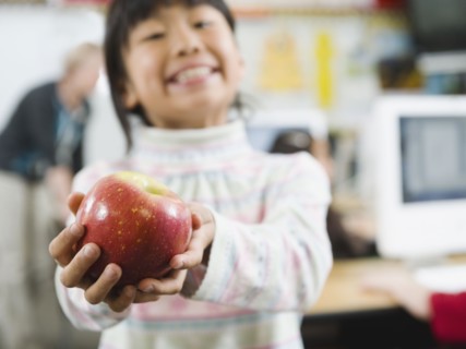 Elementary student holding an apple in her hand.