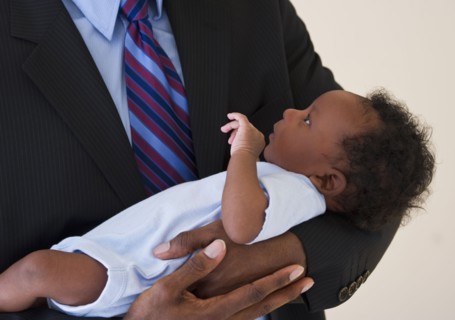 Businessman holding baby. Photo : Daniel Grill