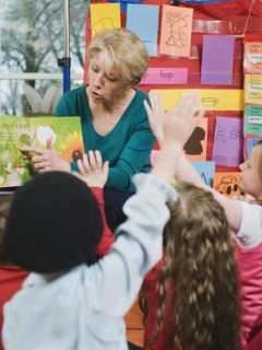 Elementary school teacher reading book to students.