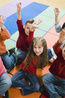Elementary school students raising their hands.