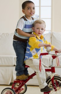 Two children on a tricycle. Photo : Chris Grill
