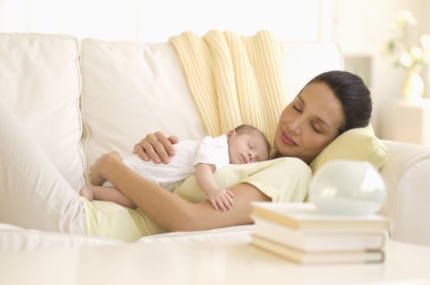 Mother and baby napping on couch.