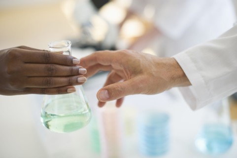 Hand passing beaker to another hand.