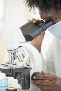 Researcher looking at specimen through microscope.