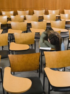 College student sleeping in empty lecture hall.