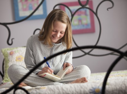Young girl writing in her diary. Photo : Mike Kemp