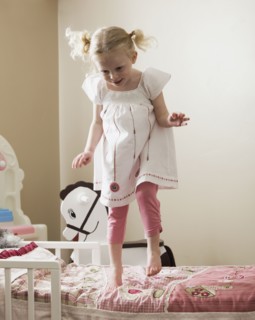 Young girl dancing on her bed. Photo : Mike Kemp