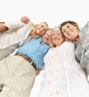 Four friends standing with their arms around each other. Photo : momentimages