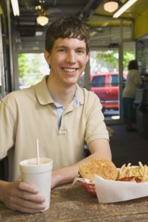 Teenage boy eating at fast food restaurant. Photo : Stewart Cohen