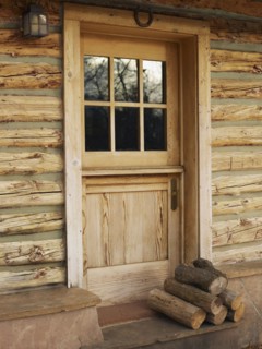 Firewood in front of door of log cabin. Photo : John Kelly