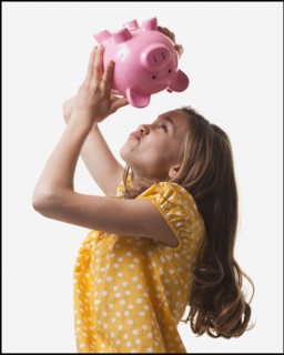 Teenage girl trying to get money out of piggy bank. Photo : Mike Kemp