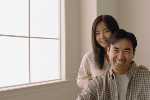 Happy couple standing by the window in their home. Photo : Rob Lewine
