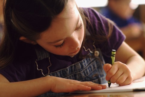 Elementary school student coloring with green crayon. Photo : Rob Lewine