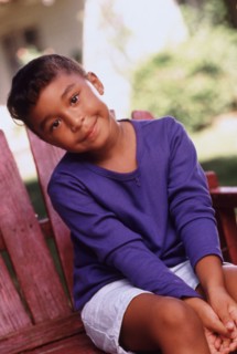 Cute young girl sitting outdoors on chair in summer. Photo : Rob Lewine