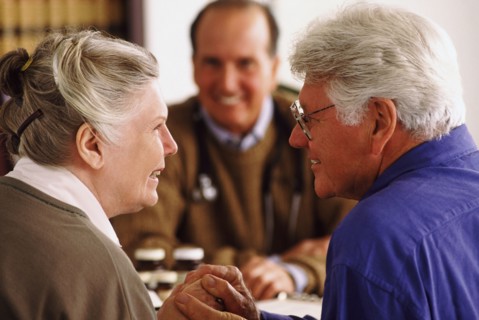 Senior couple sitting at desk across from doctor. Photo : Rob Lewine