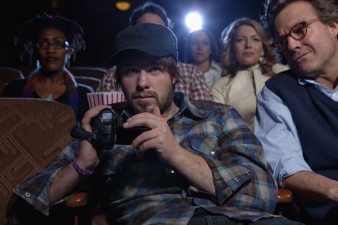 Man using video recorder in movie theatre. Photo : Dan Bannister