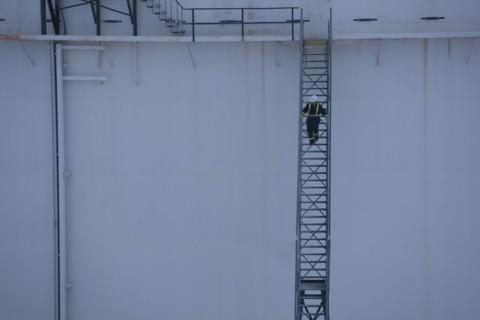 Worker walking down stairs on an oil tank. Photo : Dan Bannister