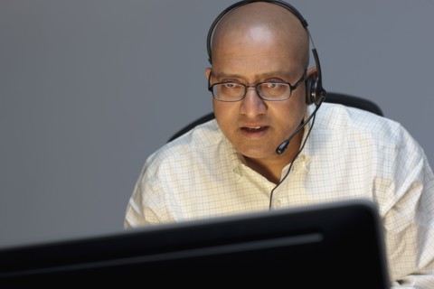 Man wearing headset working on computer. Photo : Dan Bannister