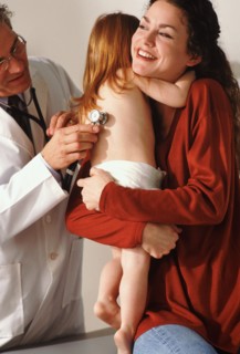 Toddler hugging her mother during medical check-up. Photo : Rob Lewine